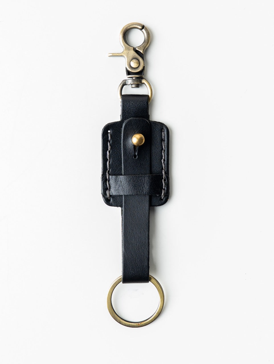 Black leather key fob with brass hardware on a white background